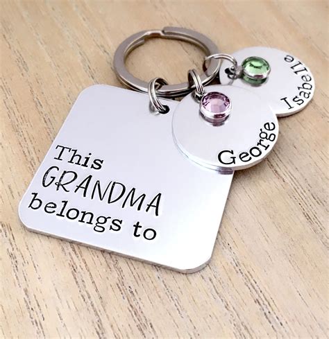 this grandma belongs to two keychains on top of a wooden table with the words this grandma
