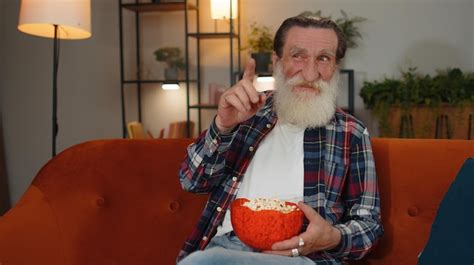 Premium Photo Man Sitting On Couch Eating Popcorn And Watching