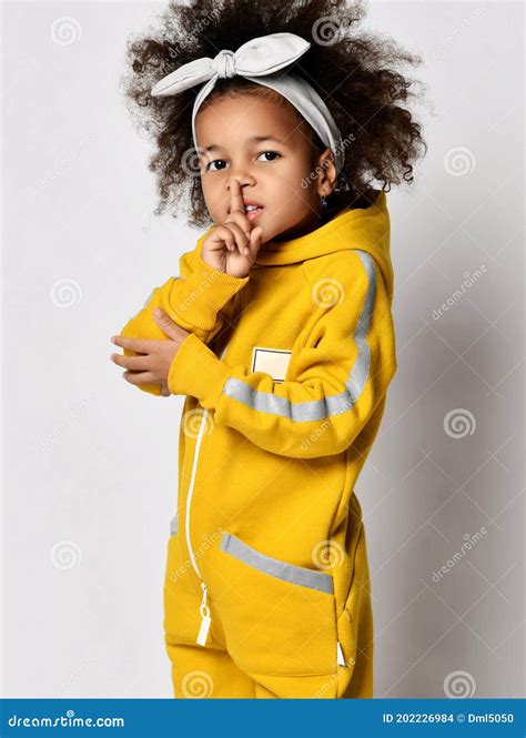 Pretty Small Curly Mulatto African Girl In Warm Yellow Jumpsuit And