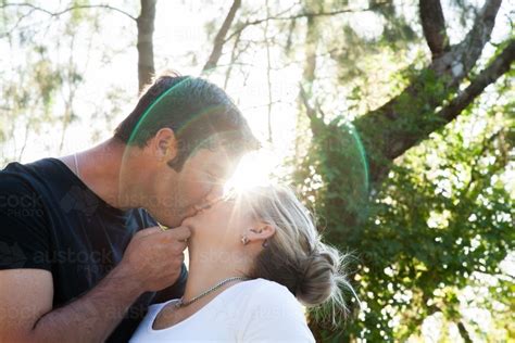 image of couple kissing outside with lens flare austockphoto