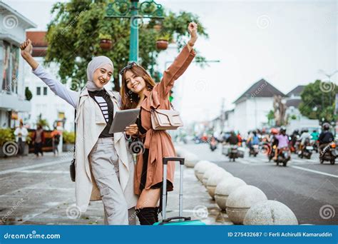 Two Happy Travellers Raising Her Hands While Standing Together At The