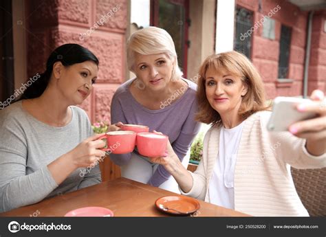 Beautiful Mature Women Drinking Coffee While Taking Selfie In Cafe