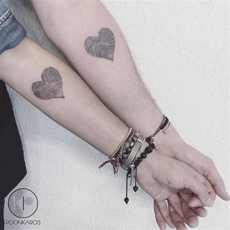 Two People Are Holding Hands With Tattoos On Their Arms And Armbands