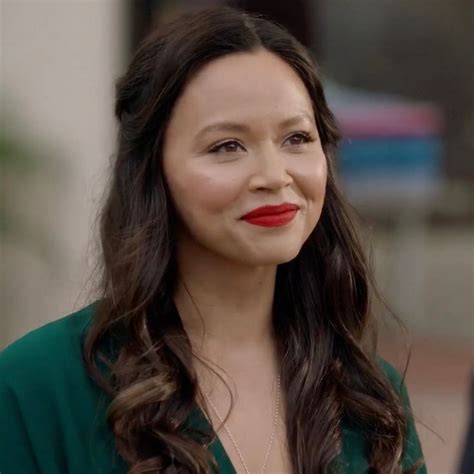 A Woman With Long Dark Hair Wearing A Green Shirt And Red Lipstick On