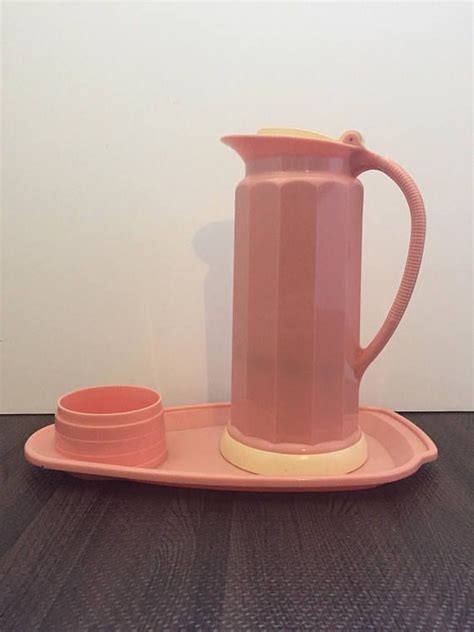 A Pink Coffee Pot And Two Cups On A Plate