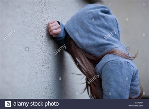 Sad Girl In Hoodie With Face Hidden Leaning Against A