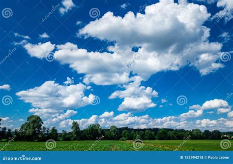 Dramatic Scenic Clouds In An Intense Blue Sky Over Green Landscape