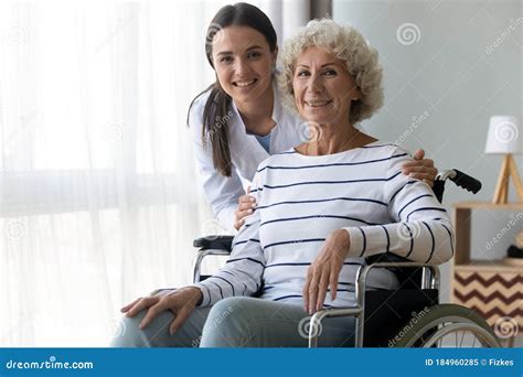 Caring Nurse Hug Elderly Disabled Woman In Wheelchair Posing Indoors Stock Image Image Of Aged
