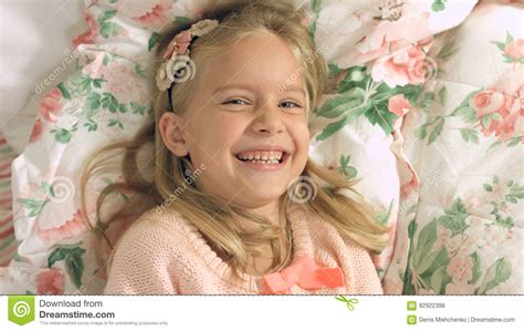 Adorable Little Girl Lying On The Bed And Laughing Gaily Stock Photo - Image of love, cute: 82922398