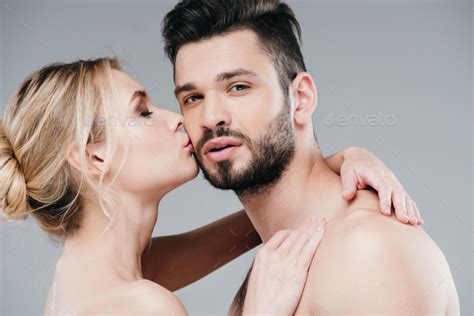 Attractive Nude Woman Kissing Cheek Of Handsome Bearded Man On Grey