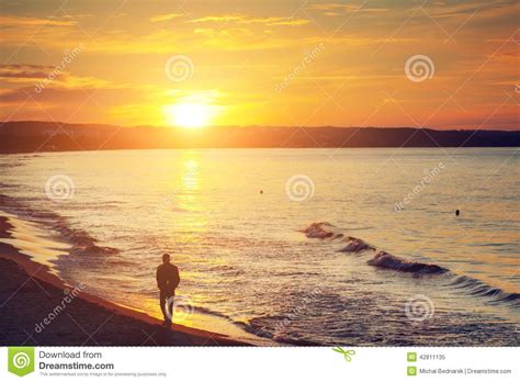 Man Walking Alone On The Beach At Sunset Calm Sea Stock