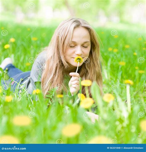 Beautiful Girl Lying On The Grass And Smelling Dandelion Stock Photo