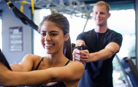 A Man And Woman In The Gym Doing Exercises For Their Muscles Smiling At The Camera