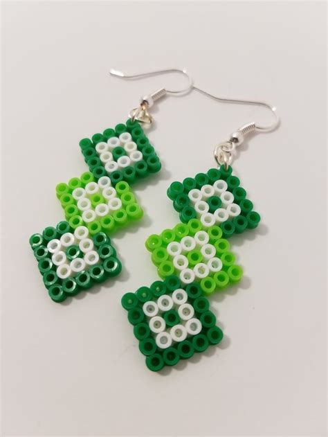 Two Green And White Beads Are Hanging From Earrings