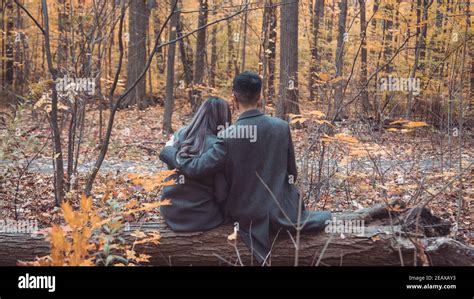 Couple In The Woods With Fall Colors Being Intimate In A Forest Setting By Romantically Posing