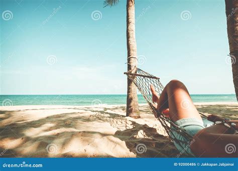 Beautiful Tanned Legs Of Women Relax On Hammock At Sandy Tropical