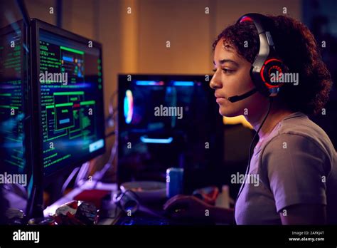 Female Teenage Hacker Sitting In Front Of Computer Screens Bypassing