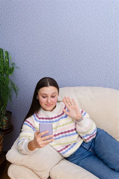 Happy Laughing Teen Girl Waving Hand Having Online Video Call On Her Smartphone While Relaxing