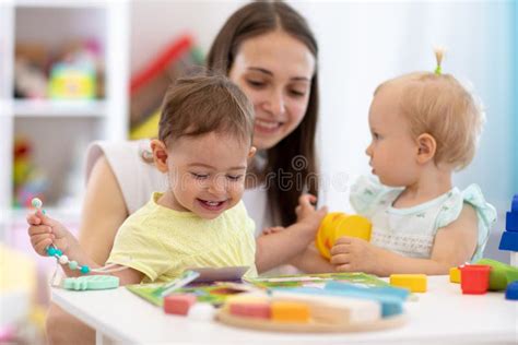Happy Babies In Day Care Group Of Kids Playing Toys With Kindergarten
