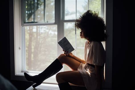 femme qui lit un livre sur le bord de la fenêtre Le Cahier