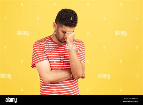 Sorrowful Hopeless Man In Striped T Shirt Lowering His Head Hiding Eyes