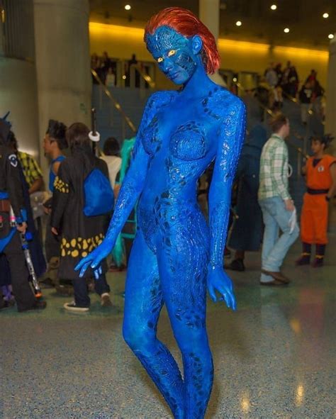 A Woman With Blue Paint On Her Body Is Standing In The Middle Of A Crowd