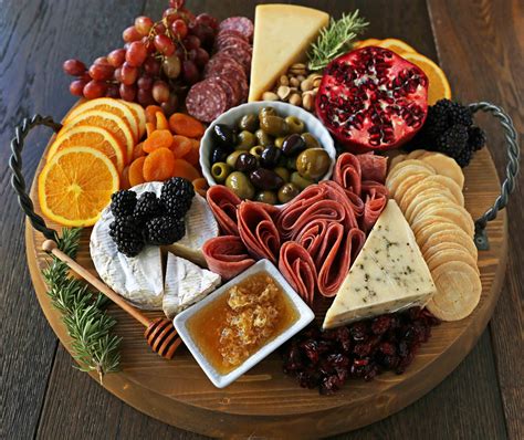 An Assortment Of Cheeses Meats And Fruit Arranged On A Platter