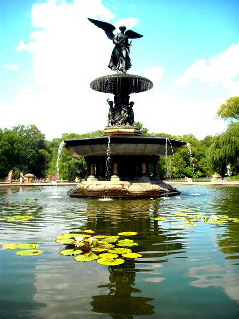 A Fountain With A Statue In The Middle Surrounded By Lily Pads