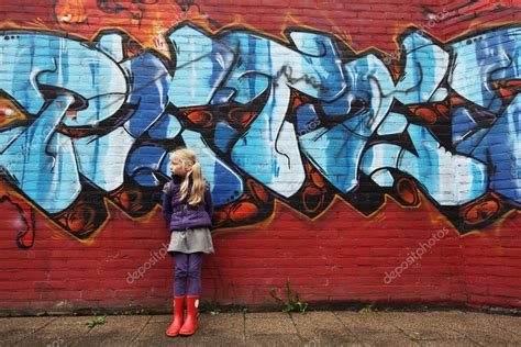 Little Girl In Front Of A Brick Wall With Graffiti — Stock Photo