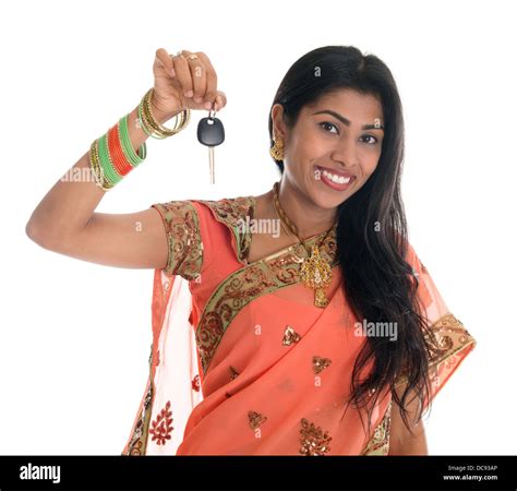 attractive traditional indian woman in sari holding her first own car key isolated on white