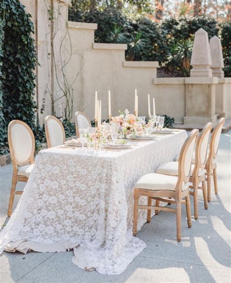 A Table Set Up With White Linens And Candles For An Elegant Wedding Reception In The Garden