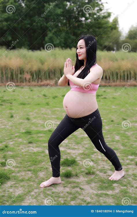 Happy Smile Asian Chinese Pregnant Woman In Yoga Dress Do Meditation In Nature Sit On Grass Lawn