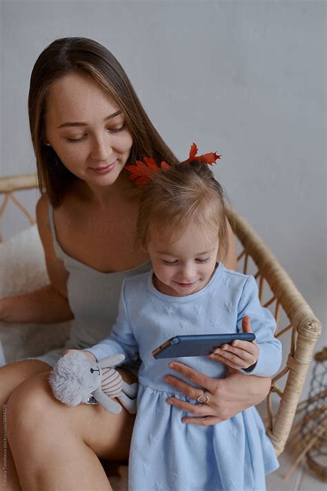 Mother And Daughter Sit In A Beautiful Wicker Chair And Look At The Phone Stock Image Everypixel