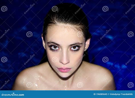 Close Up Fashion Portrait Of A Girl In The Pool Woman Posing Against The Blue Background Of