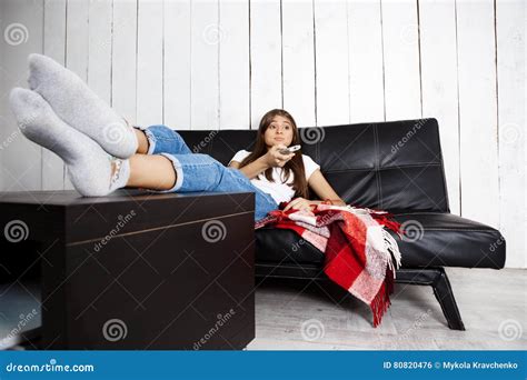 Bored Pretty Girl Watching Tv Sitting On Sofa At Home Stock Photo