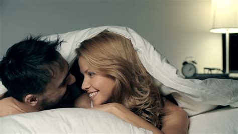 Close Up Of Couple Cuddling Under The Sheets And Looking At Camera Stock Footage Video 9026548