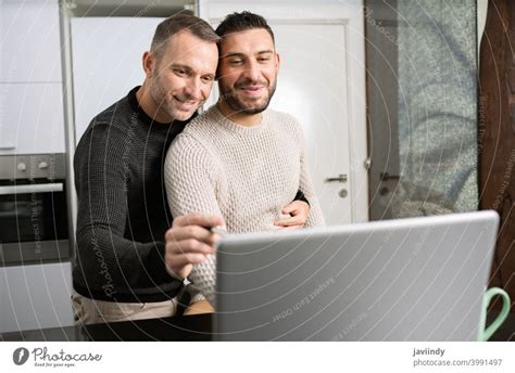 Romantic Gay Couple Working Together At Home With Their Laptops A