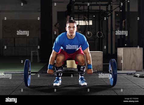Portrait Of Determined Male Athlete Lifting Barbell In Gym Stock Photo