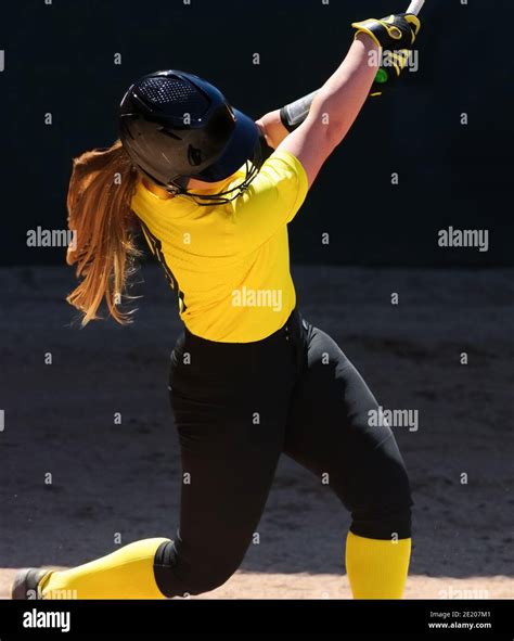 A Female Baseball Player Is Swinging The Bat During Tournament Play