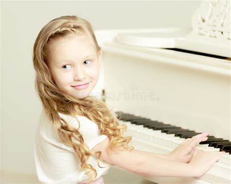 A Little Girl Is Sitting At The White Piano Stock Photo Image Of