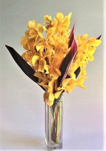 Bright Yellow Mokara Orchids Designed In A Stylish Rectangle Vase Accented With Tropical Foliage