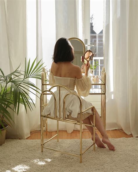 A Woman Sitting On A Chair In Front Of A Mirror