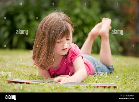 Little Girl Laying In Grass And Reading Stock Photo Alamy