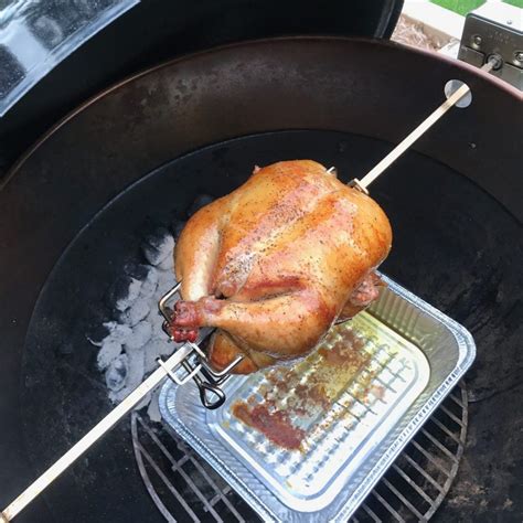 A Chicken Is Being Cooked On An Outdoor Bbq Grill With Tongs In It