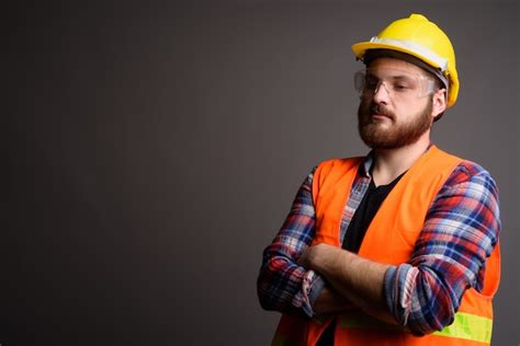 Premium Photo Young Bearded Construction Worker Against Gray Wall
