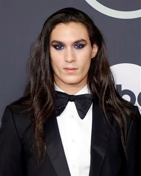 A Man With Long Hair Wearing A Black Tuxedo And Blue Eyeshadow
