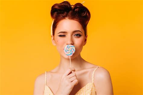 free photo elegant ginger girl licking lollipop front view of enthusiastic woman with hard candy
