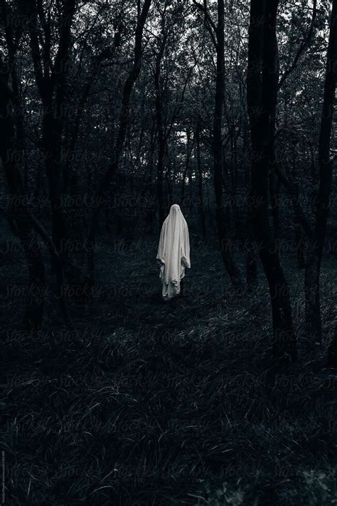 A Ghostly Person Walking Through The Woods In Black And White