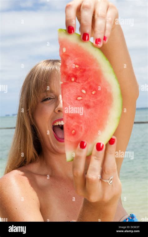 A Caucasian Woman Screams While Holding Up A Red Juicy Slice Of