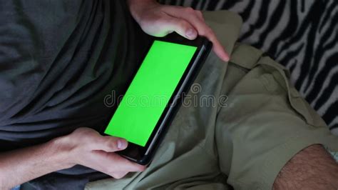Man Is Laying On Couch At Home And Watch On Tablet With Green Screen